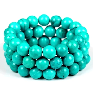 Detailed close-up of triple-layered turquoise bead bracelets with natural mineral textures