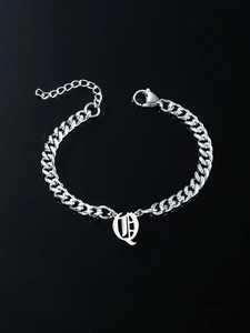 Macro shot of silver Cuban link bracelet featuring a Gothic letter pendant and lobster clasp