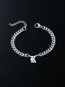 Detail of silver Gothic letter R pendant on stainless steel curb chain bracelet