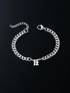 Macro detail of silver stainless steel Cuban link bracelet with Gothic letter H pendant