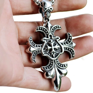 Close-up of gothic stainless steel cross necklace with skull and fleur-de-lis detail