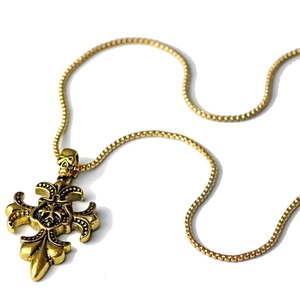 Macro detail of retro gold gothic cross pendant with skull carving on Venetian chain
