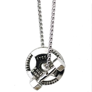 Gros plan sur le pendentif haltère en argent gravé avec une chaîne à mailles carrées