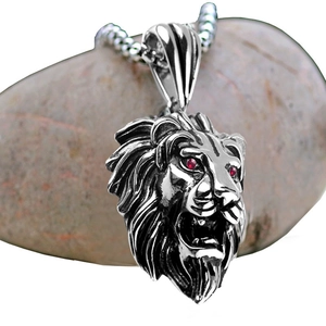 Gros plan du pendentif tête de lion avec yeux rouges sertis sur une chaîne à maillons