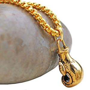 Detaillierte Makroansicht eines goldenen Boxhandschuh-Anhängers an einer feinen Box-Kette