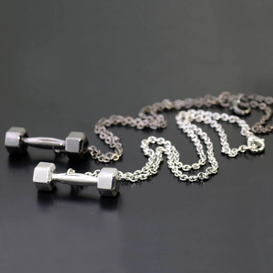 Close-up of silver and gun black dumbbell pendants on a dark reflective surface