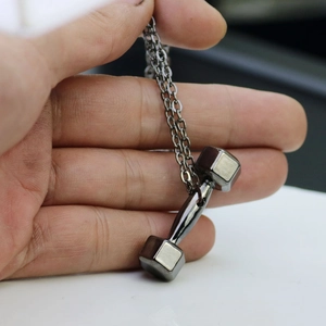 Detail view of a hand holding the gunmetal grey polished dumbbell pendant with O-chain