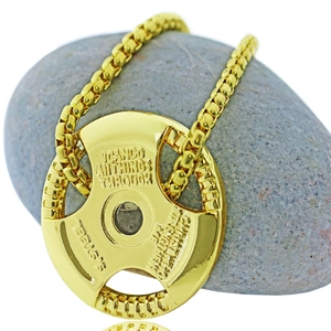 Macro detail of gold stainless steel barbell plate pendant with religious engraving