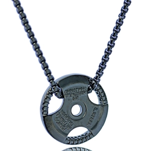 Macro detail of gun-black stainless steel barbell plate pendant with engraved quote