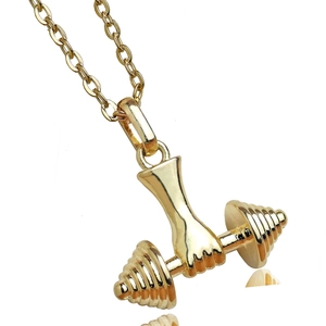 Gros plan détaillé d'un pendentif haltère doré avec une finition miroir polie