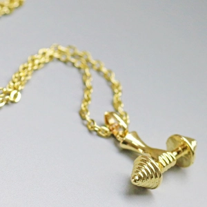 Détail d'un collier pendentif haltère doré avec chaîne pour passionnés de fitness