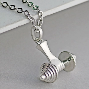 Macro shot of silver dumbbell pendant with detailed texture on a fine link chain
