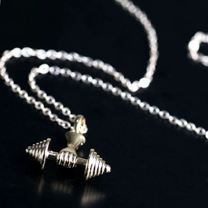 Macro view of silver dumbbell pendant necklace with realistic textured weights and chain