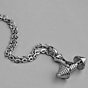 Vue détaillée du collier avec pendentif haltère argenté et chaîne croisée pour le fitness