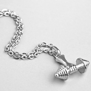 Vue macro du pendentif haltère argenté poli avec texture détaillée sur chaîne fine