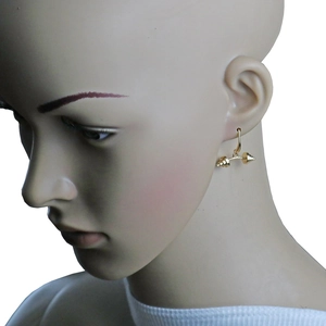 Detail view of a gold dumbbell pendant earring worn on a mannequin for fitness enthusiasts