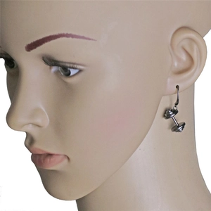 Boucle d'oreille haltère de fitness en métal gris foncé portée sur l'oreille d'un modèle
