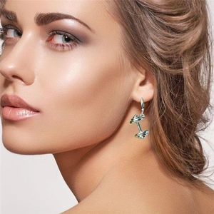 Boucles d'oreilles haltères argentées pour le fitness portées par un mannequin de profil