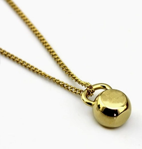 Detailed view of a gold kettlebell pendant necklace for women fitness jewelry