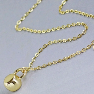 Polished gold kettlebell pendant necklace for women on a minimalist textured background