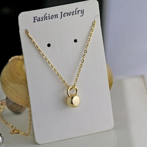 Detail of a gold kettlebell dumbbell pendant on a white jewelry display card