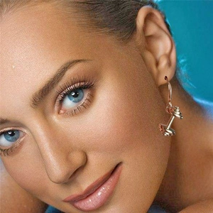Boucles d'oreilles haltères dorées sur mannequin, bijoux fitness pour femmes