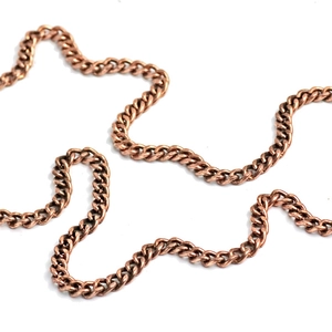Gros plan sur une chaîne gourmette en métal bronze avec une finition texturée