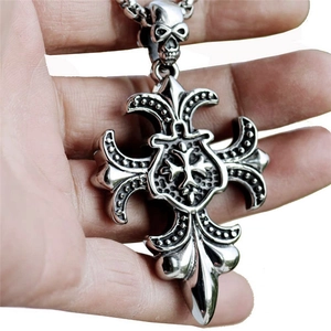 Close-up of retro gothic cross pendant with skull detail and fleur-de-lis engravings