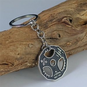 Barbell weight plate keychain with fitness slogans on a rustic wooden background