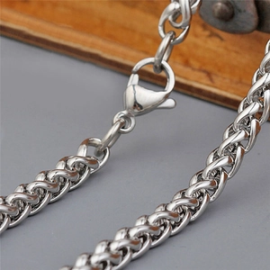 Macro detail of silver stainless steel wheat chain showing the lobster clasp and texture