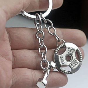 Fitness keychain with antique metal dumbbell and weight plate charms held in hand
