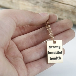 Makroaufnahme der Goldkette mit Gravur-Anhänger Strong Beautiful Health für Damen