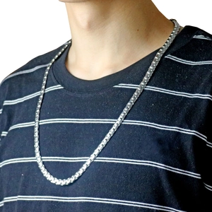 Détail d'un collier chaîne box en acier inoxydable porté par un mannequin sur un t-shirt