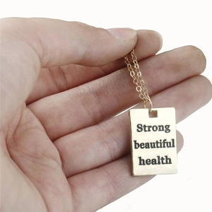 Goldene Halskette mit rechteckigem Anhänger und Gravur Strong Beautiful Health auf Weiß