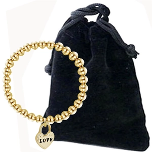Detalle de pulsera de cuentas doradas con dije de corazón y bolsa de terciopelo