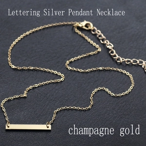 Macro view of champagne gold rectangle pendant necklace on black textured background
