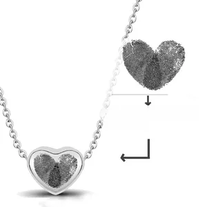 Dettaglio macro dell'incisione a cuore con impronte su collana a barra in acciaio lucido