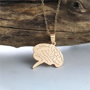Artistic golden brain pendant necklace made of stainless steel hanging on a branch
