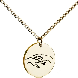 Macro shot of polished gold-plated circular pendant with delicate finger touch engraving