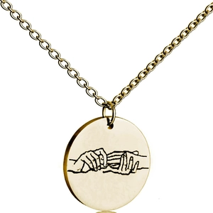 Macro detail of gold circle pendant featuring engraved hand gesture on a fine chain