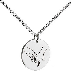 Close-up of engraved stainless steel round pendant with minimalist hand gesture line art