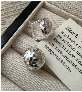Macro detail of 925 sterling silver hoop earrings with faceted geometric sphere texture