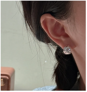 Close-up of a multifaceted silver ball earring with high-polish faceted metal finish