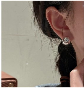 Detail of 925 sterling silver faceted ball earrings worn on ear with metallic luster