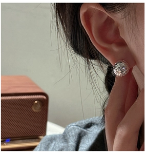 Detailed close-up of a silver disco ball stud earring with faceted geometric surface