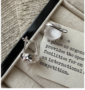 Detail of 925 sterling silver hoop earrings with diamond-cut hammer texture in a jewelry box