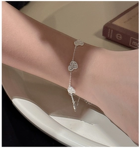 Detail of silver heart-shaped charms with textured surface on a delicate chain bracelet