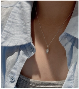 Détail du collier avec pendentif seau en argent S925 porté sur une chemise bleue décontractée