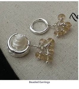 Macro detail of silver beaded earrings with natural brown stones and shell pendants