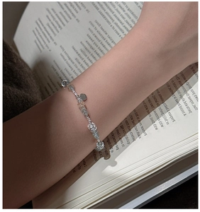 Detail of beaded S925 silver bracelet with blue aquamarine stones on a book